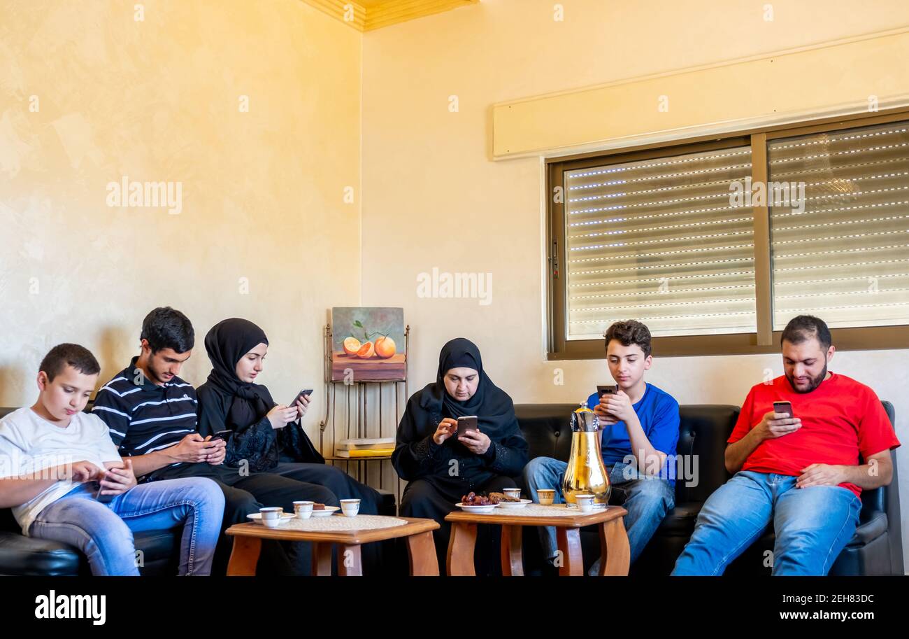 Famille arabe assis ensemble mais chacun d'eux est sur leur téléphone Banque D'Images