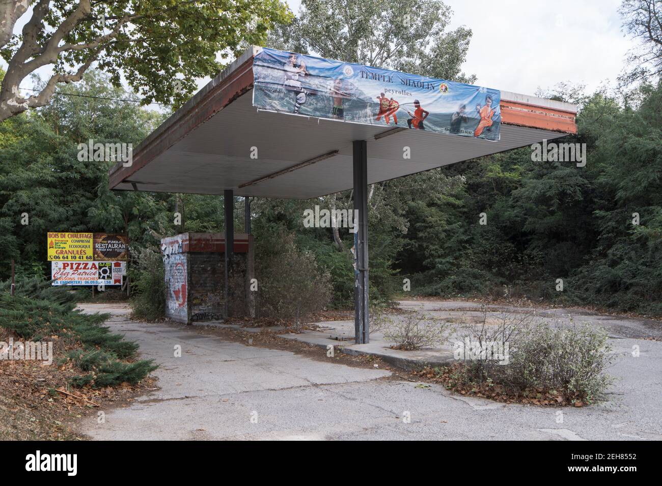Une station-service abandonnée est presque entièrement couverte par la nature Banque D'Images
