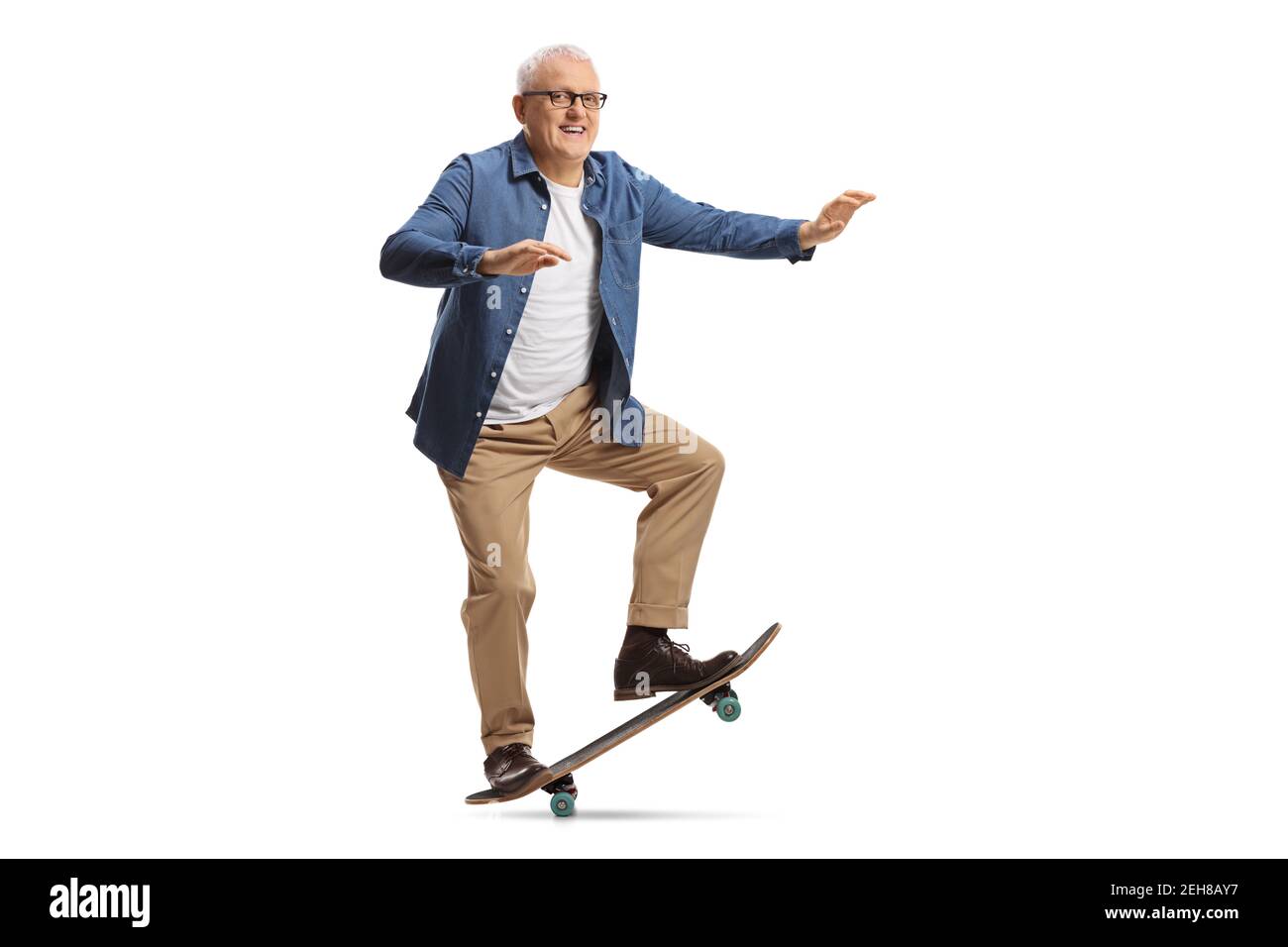 Portrait complet d'un homme mûr à bord d'un skateboard et souriant isolé sur fond blanc Banque D'Images