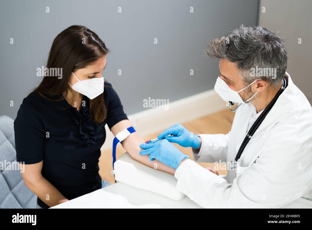 Prélèvement sanguin par le médecin en laboratoire dans le masque facial Banque D'Images