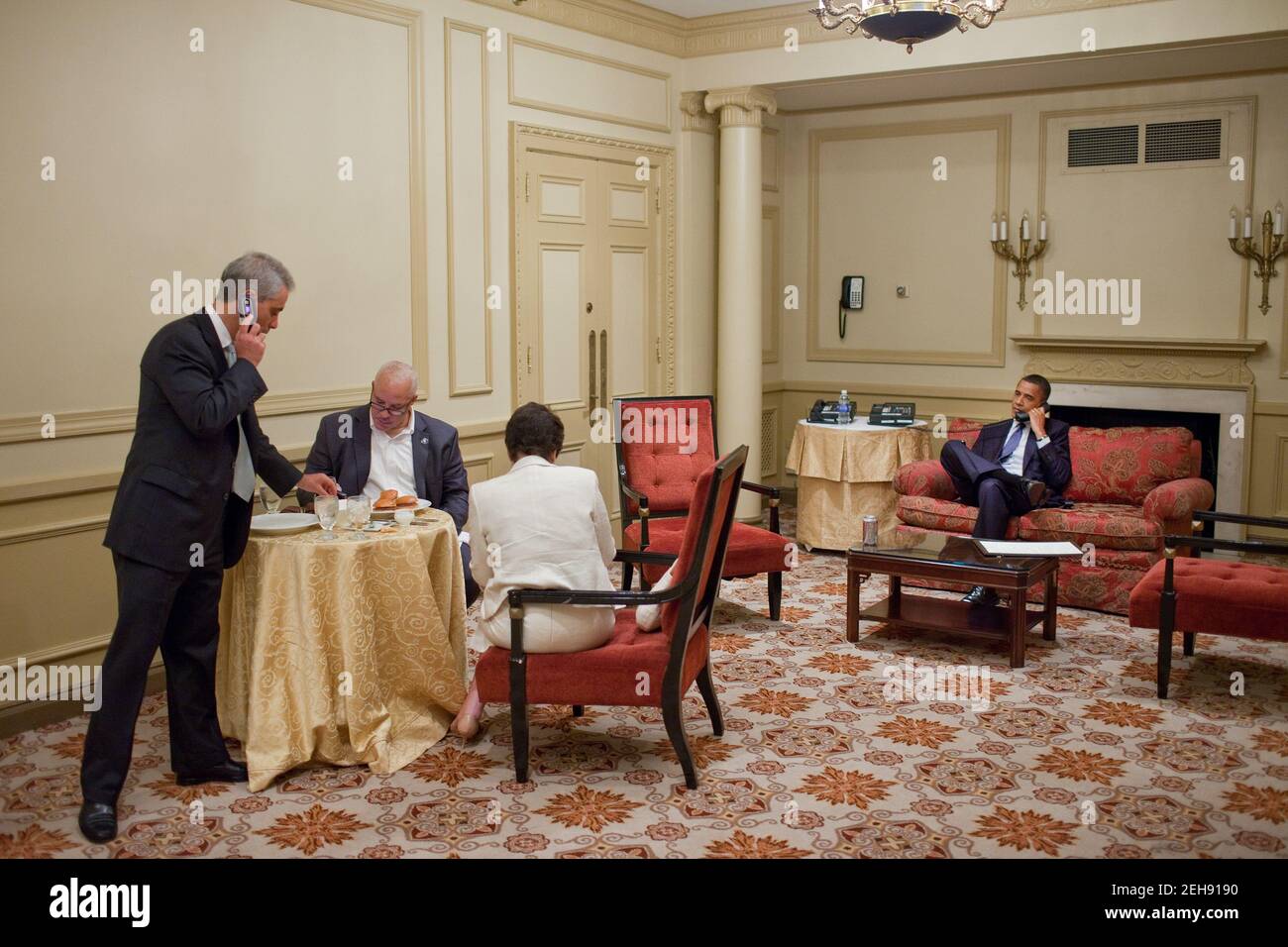 Le président Barack Obama parle au téléphone au Palmer House Hilton à Chicago, dans l'Illinois, le 5 août 2010. De gauche à droite, Rahm Emanuel, Eric Whitaker et Valerie Jarrett, conseillère principale, travaillent à proximité. Banque D'Images