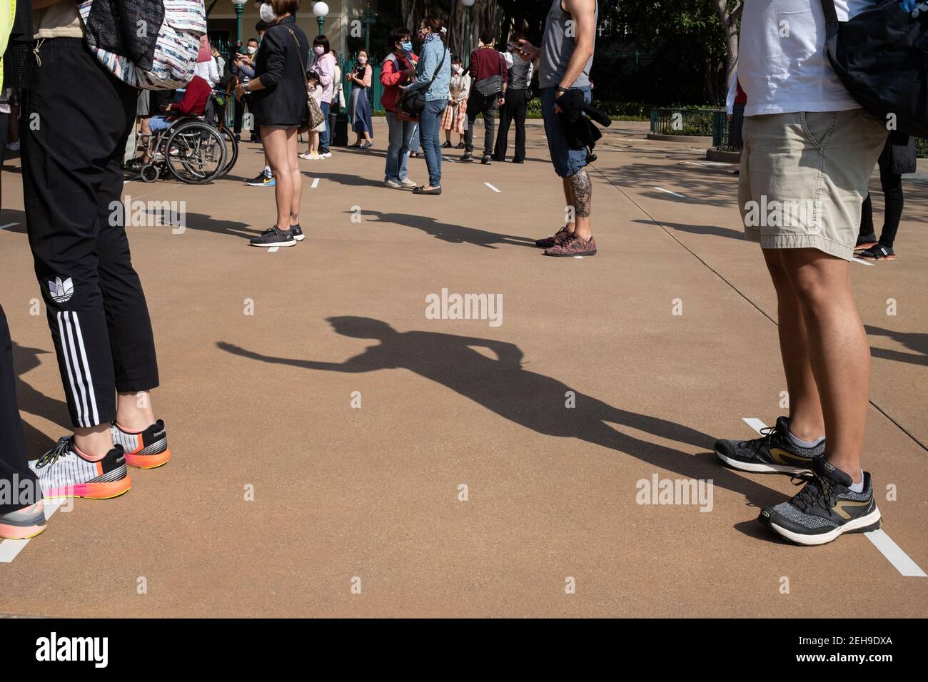 Les visiteurs se tenant dans des lieux de distanciation sociale pendant qu'ils font la queue pour entrer lors de la réouverture du parc Disneyland de Hong Kong alors que le gouvernement perd les mesures de distanciation sociale du coronavirus (Covid-19). Banque D'Images