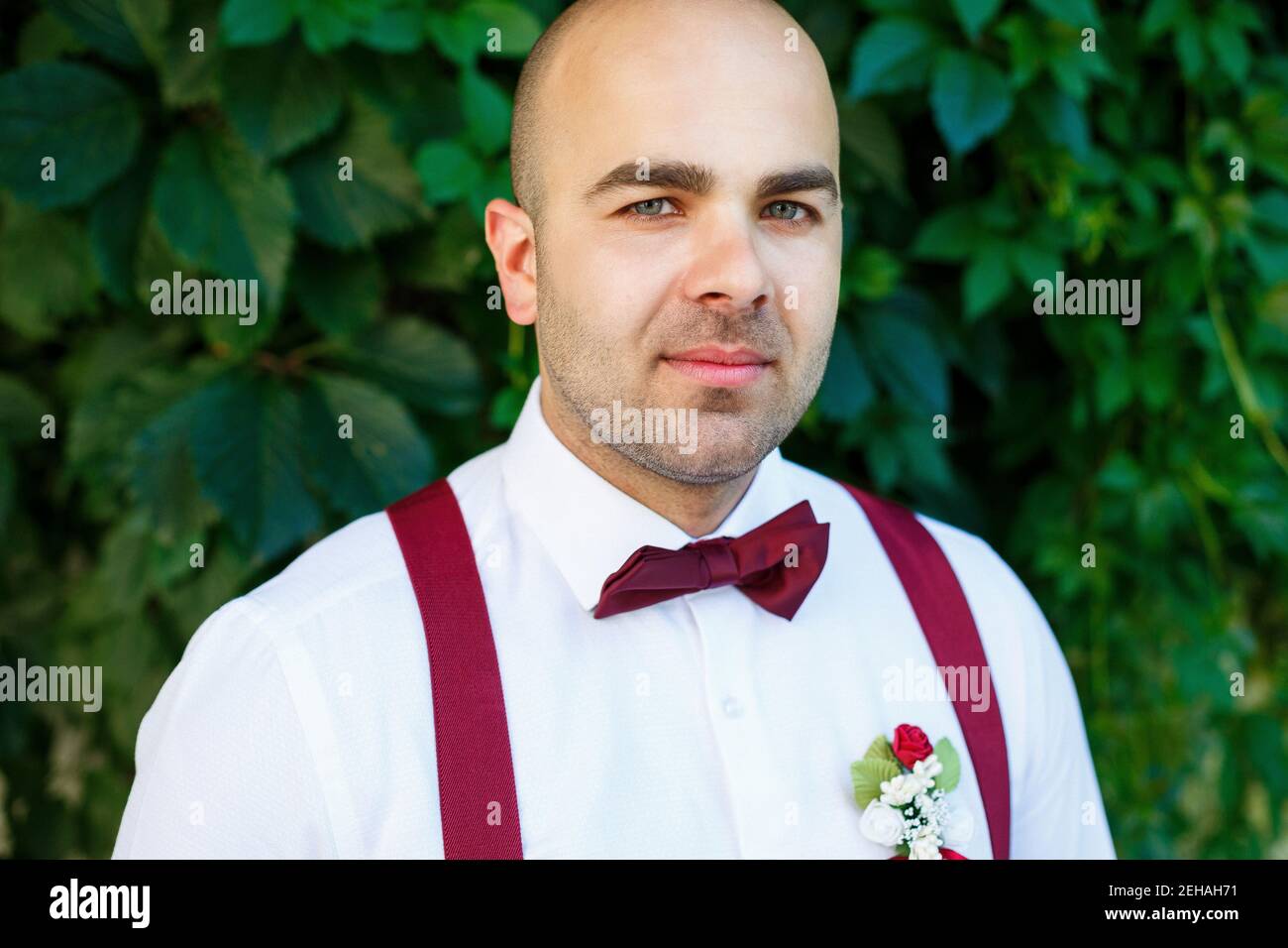 Portrait d'un marié avec un noeud papillon rouge et des bretelles. Il est  confiant avec un sourire sur son visage. Élégant homme barbu tendance dans  une chemise blanche Photo Stock - Alamy