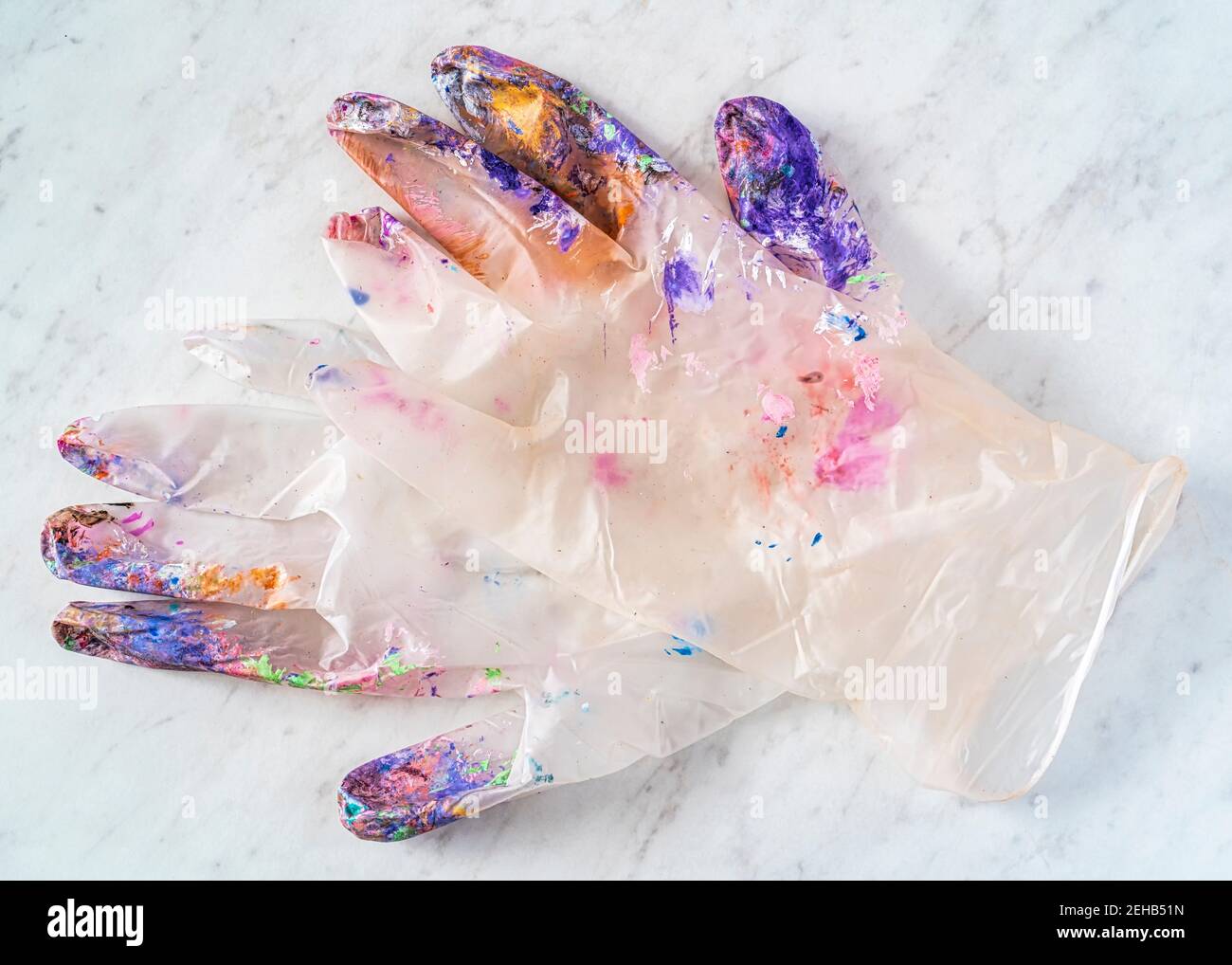 Gants en latex transparent d'un artiste recouverts de peinture. Banque D'Images