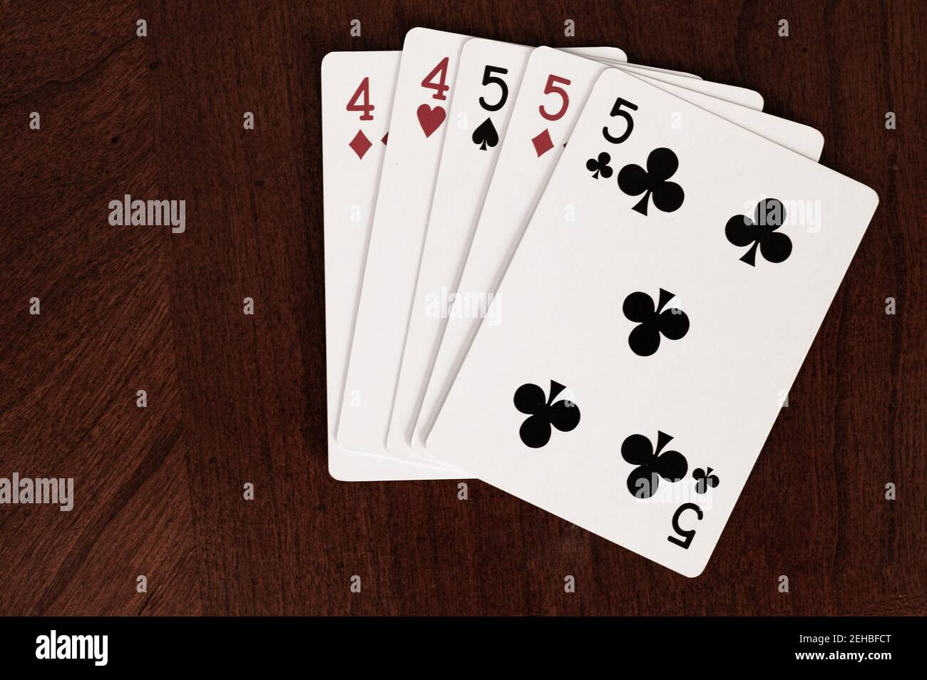 Jeux de cartes avec une maison complète de fours et de fives sur table en bois Banque D'Images