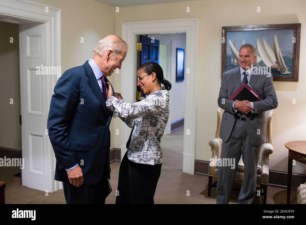 Susan E. Rice, conseillère à la sécurité nationale, aide le vice-président Joe Biden à trouver une place sur sa veste de costume, dans un hall à l'extérieur du bureau ovale, le 2 août 2013. Robert Cardillo, directeur adjoint du renseignement national pour l'intégration du renseignement, regarde à droite. Banque D'Images