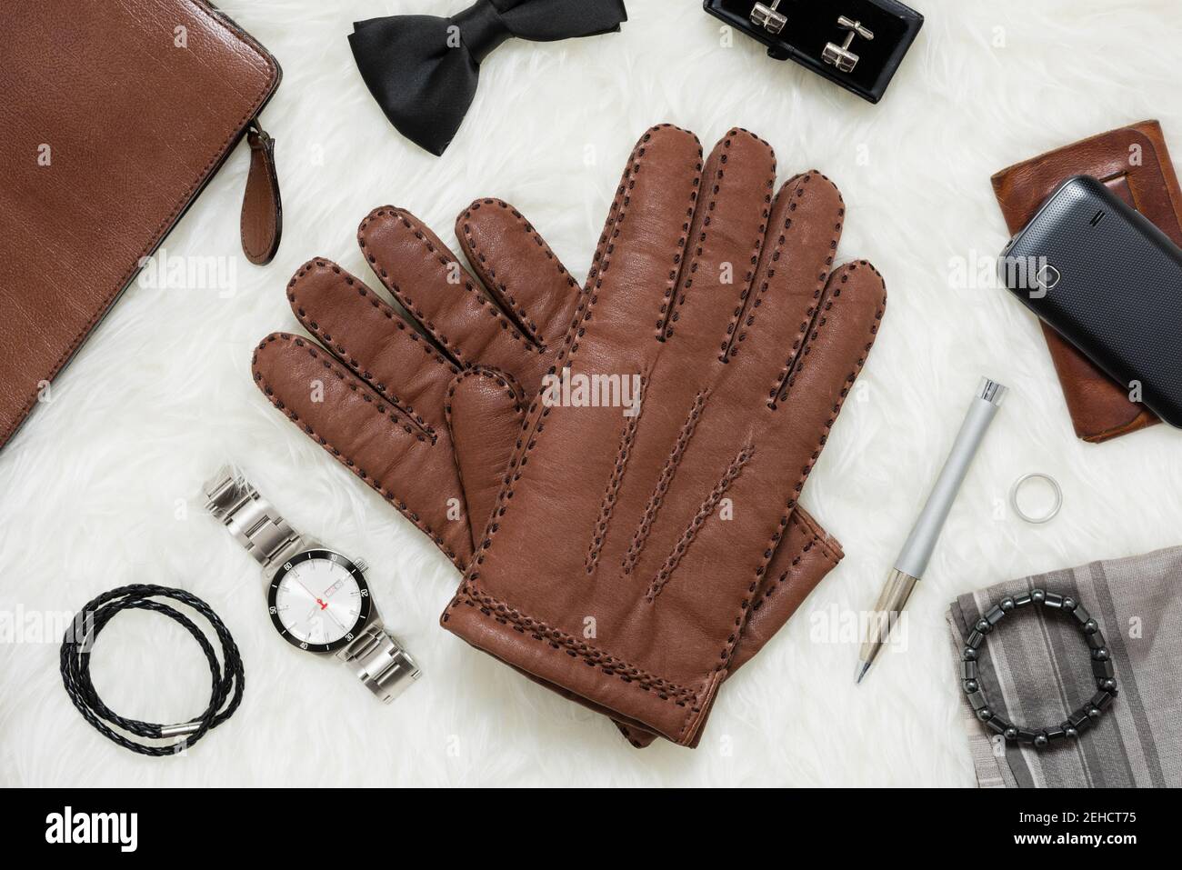 Paire de gants en cuir marron pour hommes et autres accessoires pour hommes sur fourrure blanche. Banque D'Images