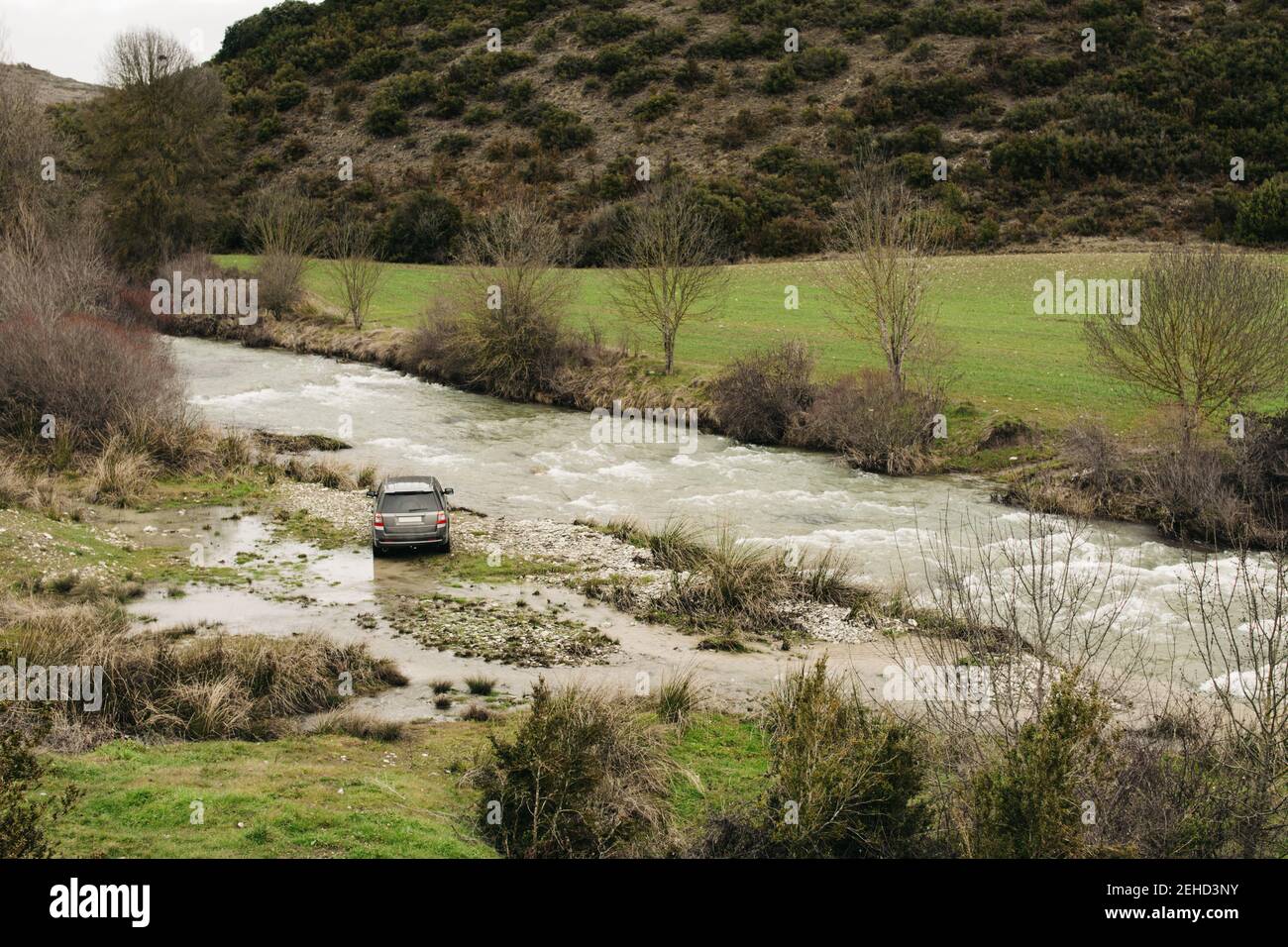 Vus moderne stationné sur la rive d'une rivière qui coule rapidement terrain vallonné recouvert de plantes Banque D'Images