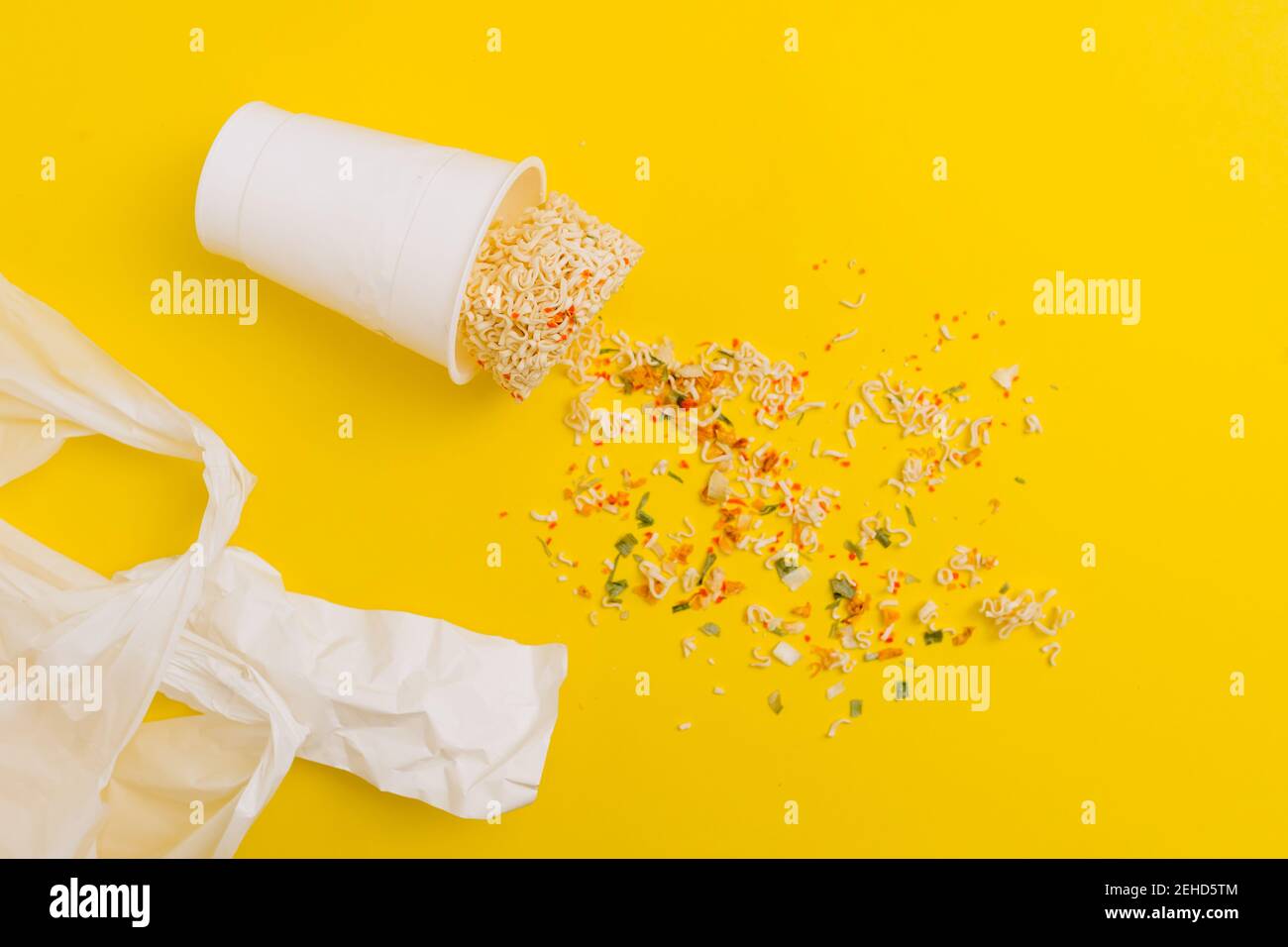 Vue de dessus composition de nouilles instantanées avec épices éparpillées près boîtier en plastique sur fond vif Banque D'Images