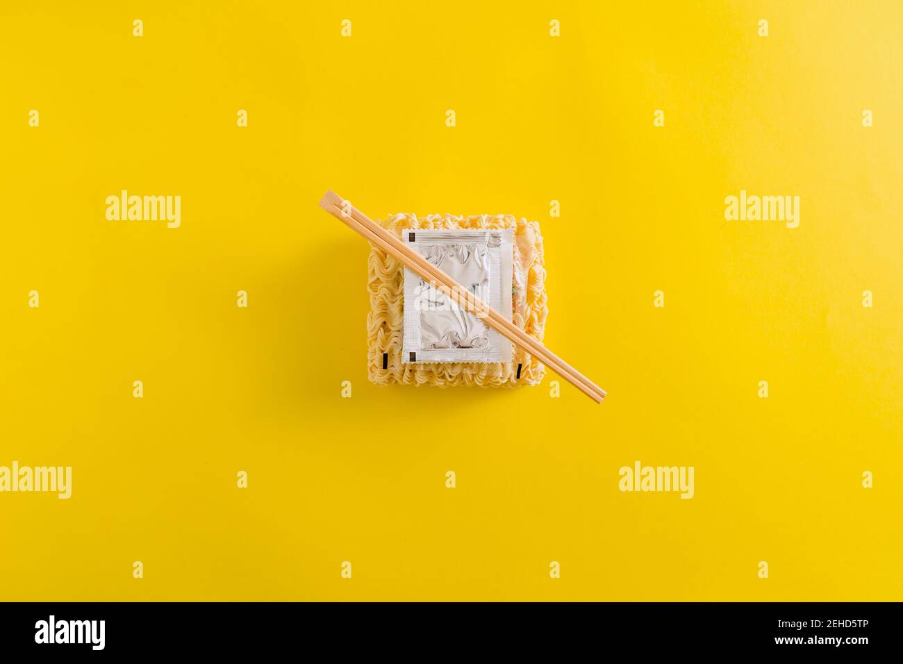 Vue de dessus de l'agencement des nouilles non cuites avec des ingrédients d'épices et colle dans des emballages en plastique sur fond jaune Banque D'Images