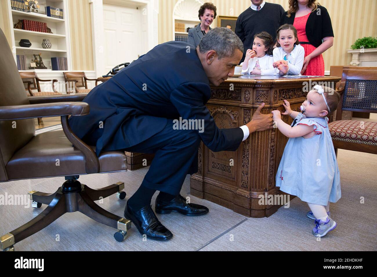 Le président Barack Obama tient la main de Lincoln Rose Pierce Smith, fille de l'ancien secrétaire de presse adjoint Jamie Smith, dans le bureau ovale, le 4 avril 2014. Elsa Smith, âgée de 5 ans, et Sage Smith, âgée de 6 ans, cousins de Lincoln, regardent de l'autre côté du bureau de Resolute. Banque D'Images