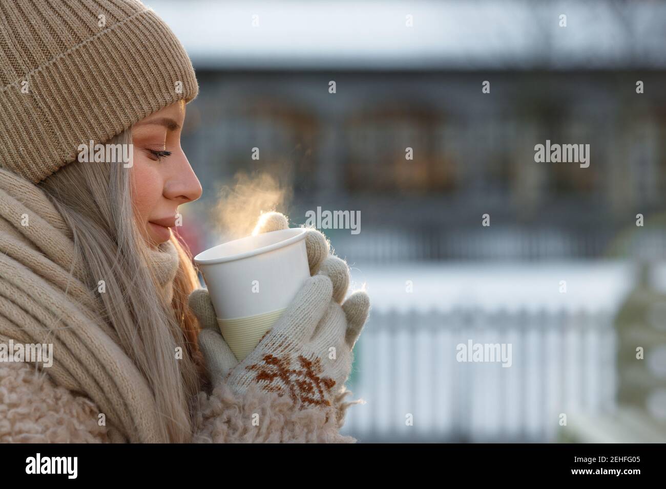 Femme porte des moufles blanches tenant une tasse de chaud blanche café ou  thé en hiver froid jour ensoleillé Photo Stock - Alamy