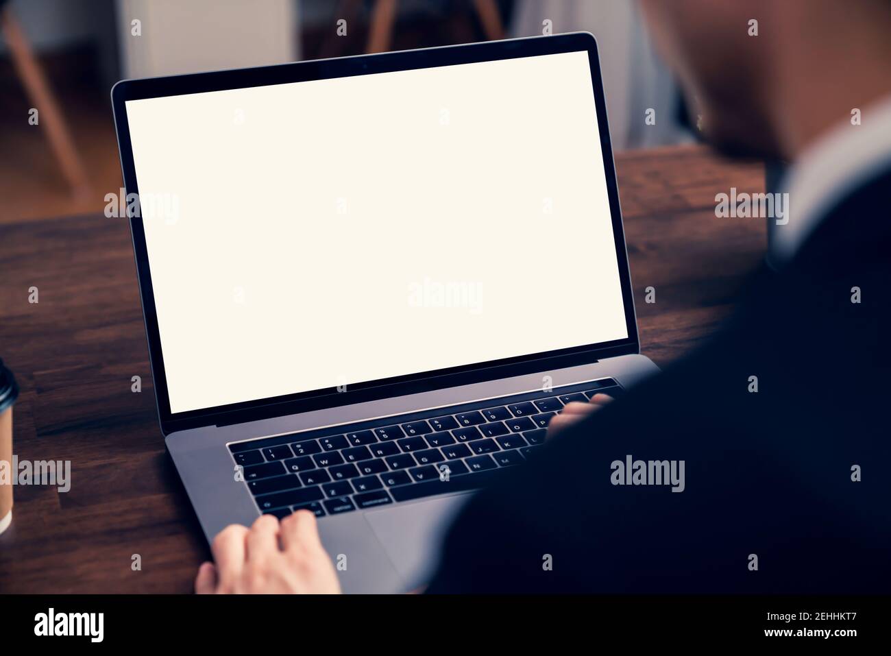 Ordinateur portable un écran vierge sur la table pour mettre sur une publicité d'ordinateur. Homme tenant une tasse de café en main et assis à un bureau dans un bureau. Banque D'Images