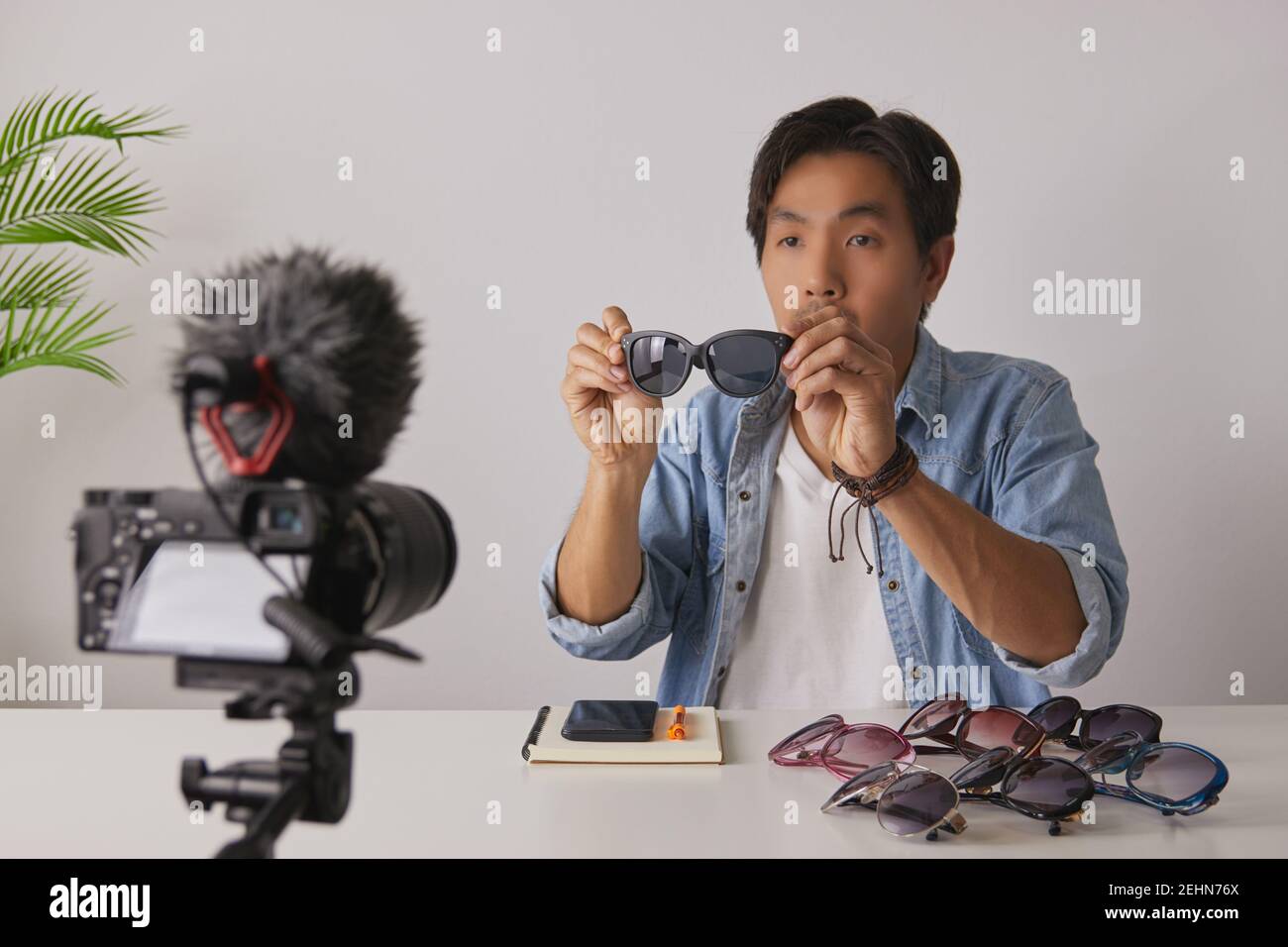 Vlogger asiatique ou Blogger en Jean chemises montrer Black Fashion lunettes pendant l'enregistrement vidéo. Freelance Online Streaming avec le client via social Me Banque D'Images