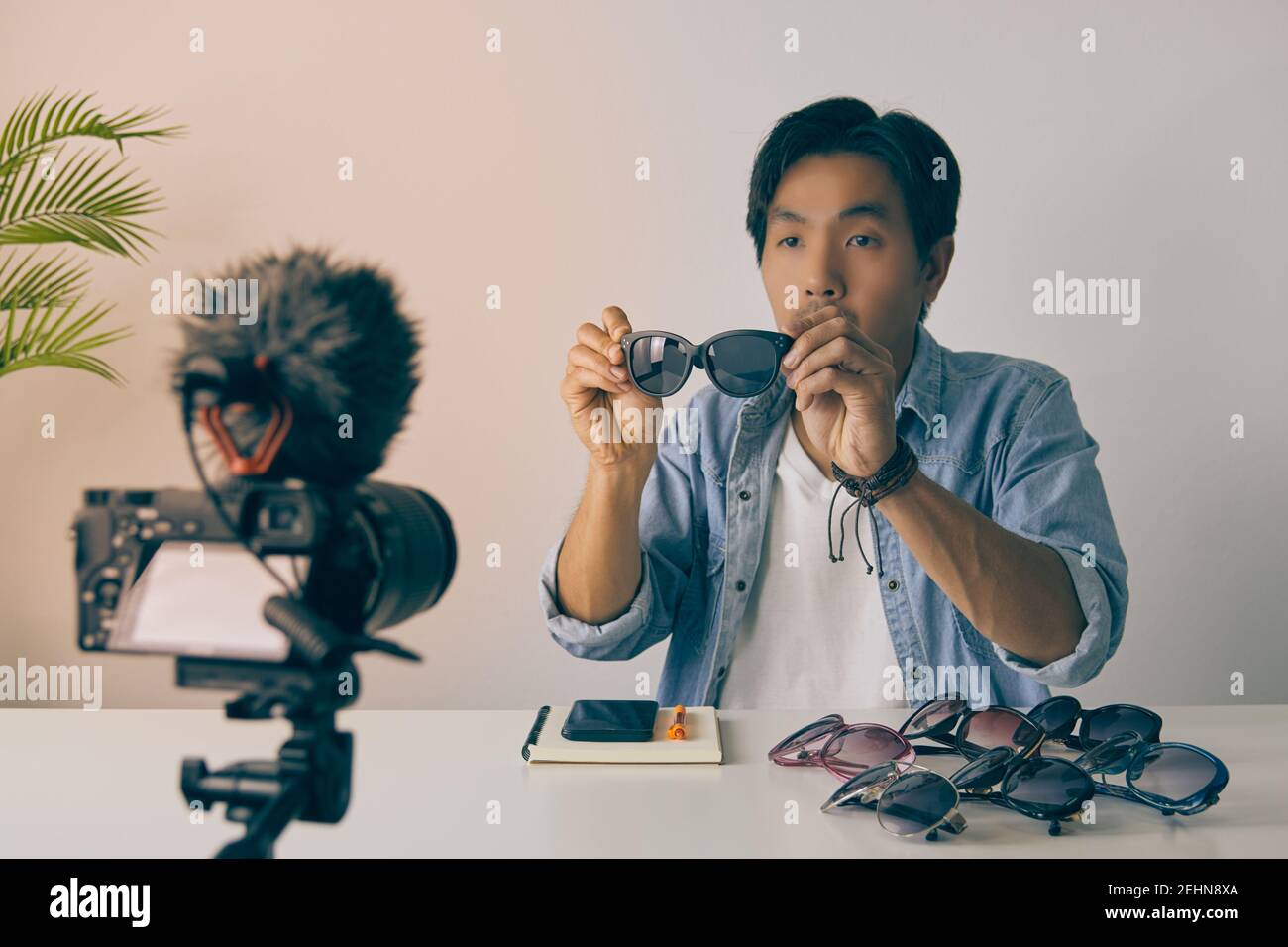 Vlogger asiatique ou Blogger en Jean chemises montrer Black Fashion lunettes pendant l'enregistrement vidéo. Freelance Online Streaming avec le client via social Me Banque D'Images