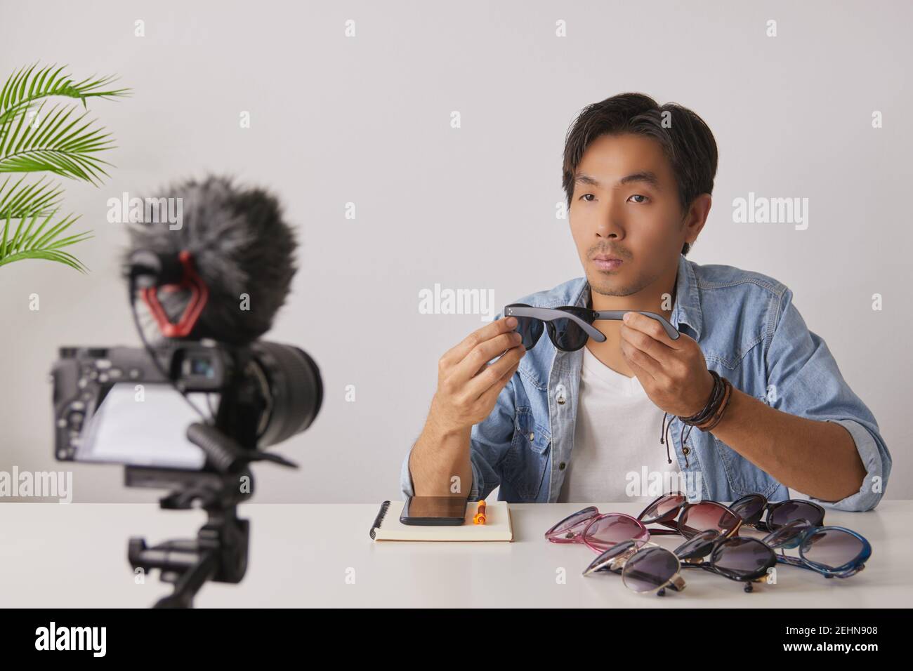 Vlogger asiatique ou Blogger dans Jean chemises examen Black Fashion lunettes et enregistrement vidéo. Freelance Online Streaming avec le client via social Me Banque D'Images