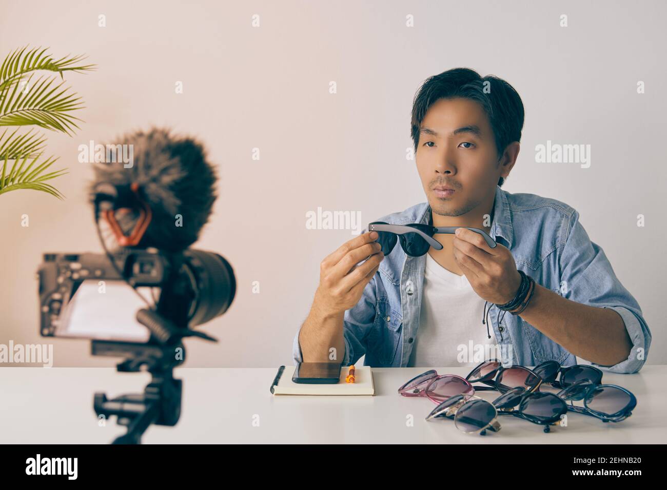 Vlogger asiatique ou Blogger dans Jean chemises examen Black Fashion lunettes et enregistrement vidéo. Freelance Online Streaming avec le client via social Me Banque D'Images