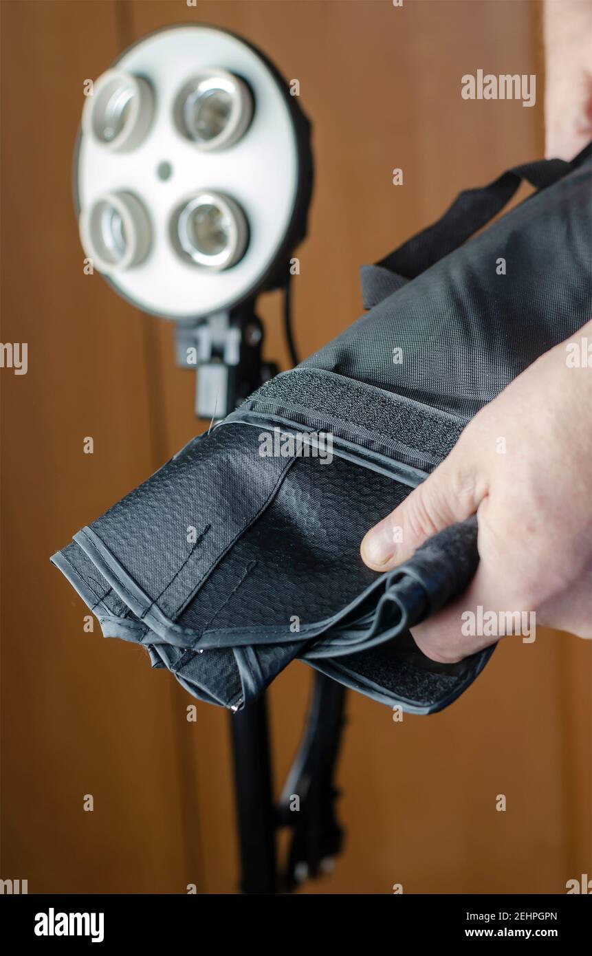 Les mains d'homme prennent le réflecteur de la softbox hors de son étui. Séquence d'assemblage d'éclairage Studio. Softbox, éclairage continu, équipement photo. Banque D'Images