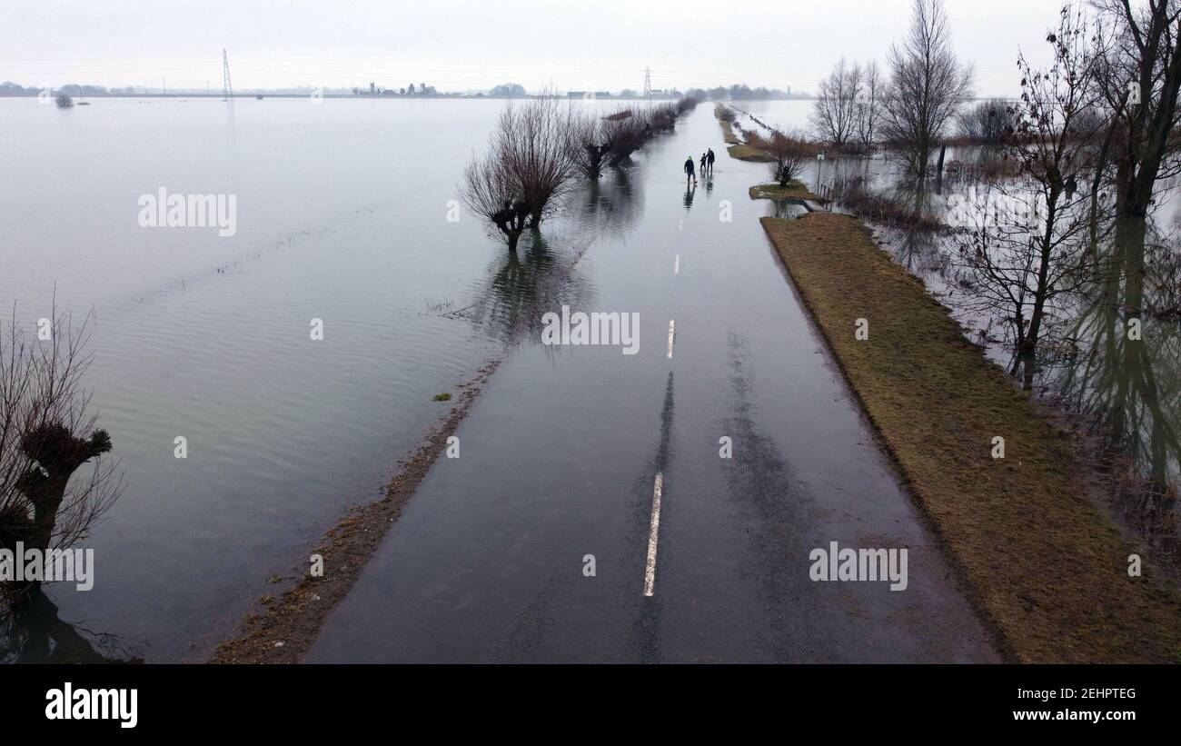 Whittlesey, Royaume-Uni. 15 février 2021. Les gens dehors pour une promenade le long d'une route inondée comme neige fondue et l'eau de crue couvre encore la route de Thorney à Whittlesey, Cambridgeshire. Les niveaux d'eau sont en baisse, mais il faudra encore quelques jours avant que la route puisse être nettoyée et rouverte. Crédit : Paul Marriott/Alay Live News Banque D'Images