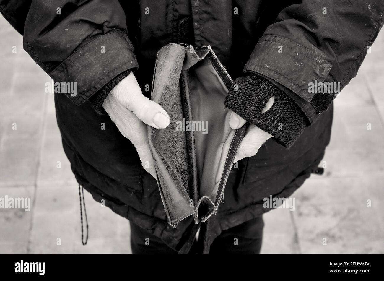 Une femme âgée tient un sac à main vide ou un portefeuille sur une table vintage en bois. Photo en noir et blanc.le concept de pauvreté à la retraite. Crise financière. Banque D'Images