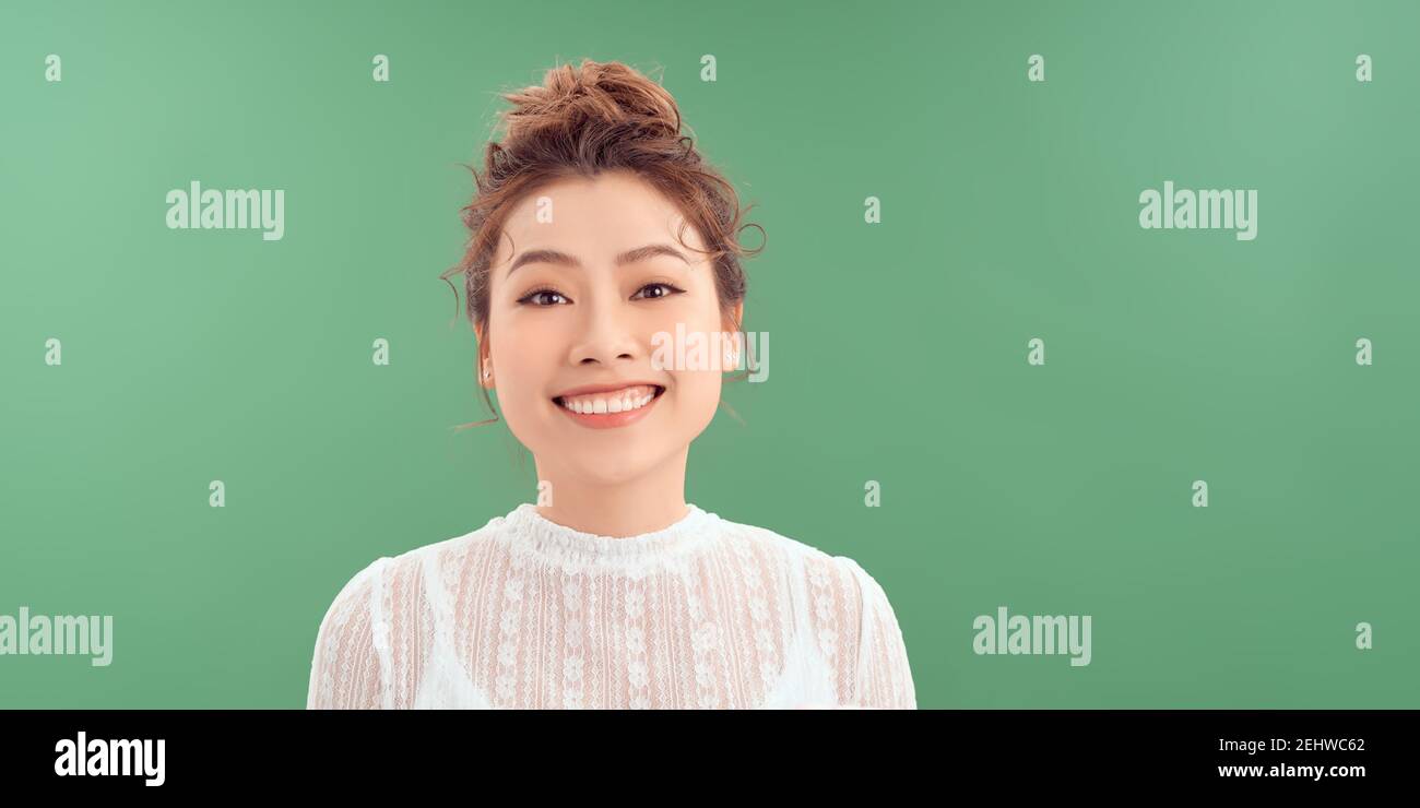 Gros plan portrait de la femme yong Portrait décontracté en vue positive, grand sourire, beau modèle posant en studio sur fond vert. Banque D'Images