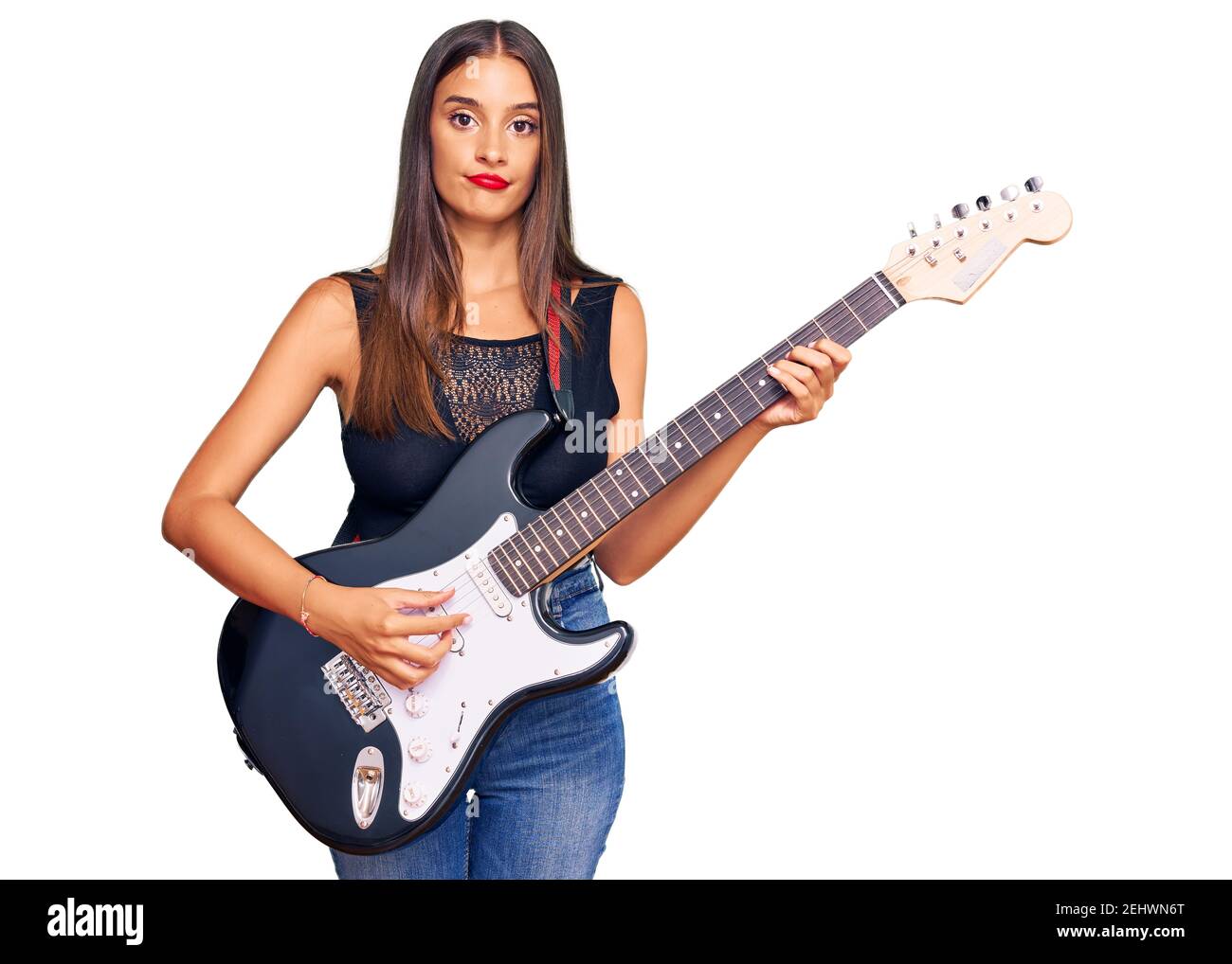 Jeune femme hispanique jouant de la guitare électrique pensée attitude et sobre expression en toute confiance Banque D'Images
