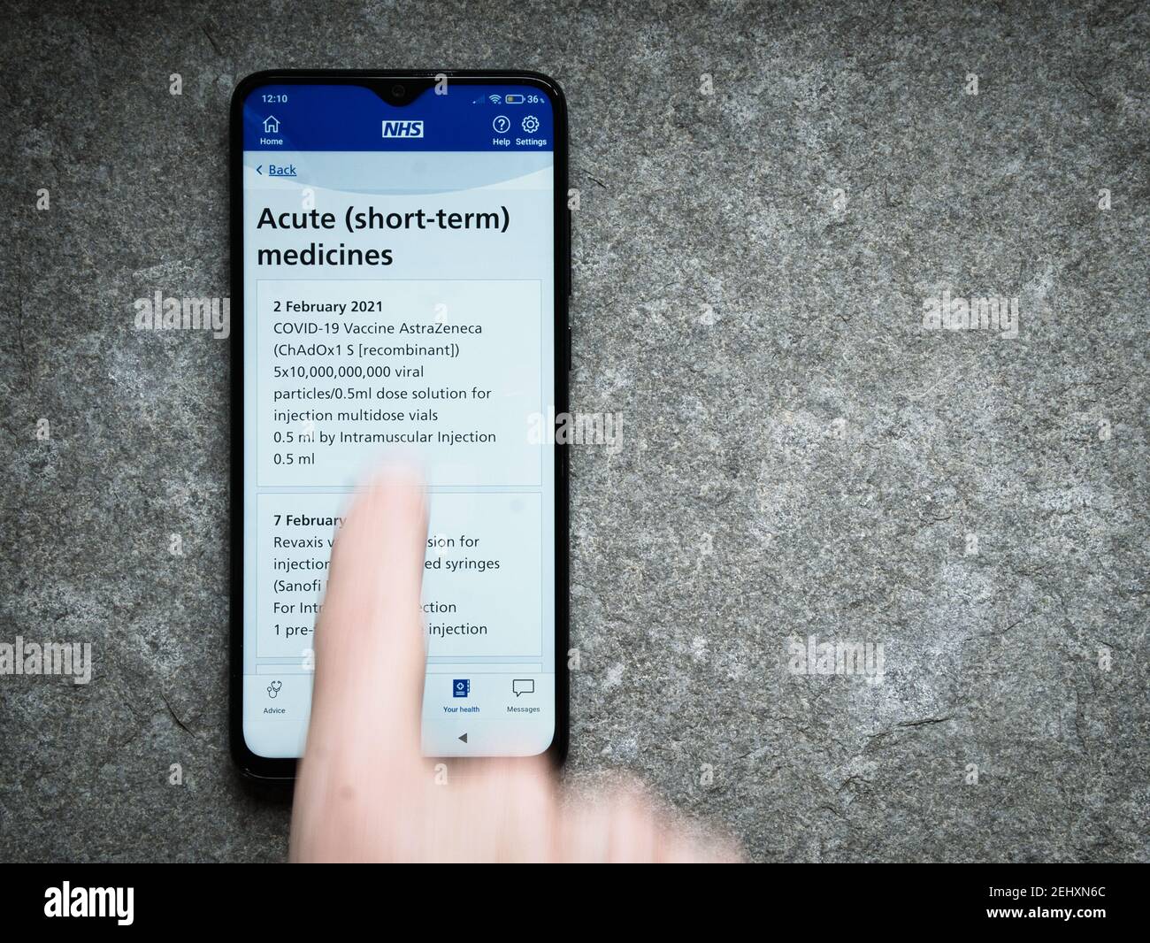 L'application pour smartphone NHS du Royaume-Uni montre des preuves d'une vaccination contre le COVID d'AstraZeneca d'Oxford donnée le 2 février 2021. Un doigt flou fait glisser Banque D'Images
