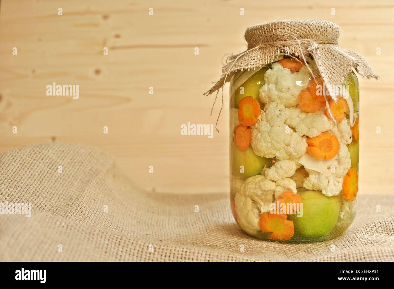 Concept de pot de cornichons de saison recouvert d'une toile de raclage pleine de tomates vertes crues de couleur, de carottes d'orange et de chou-fleur blanc. Banque D'Images