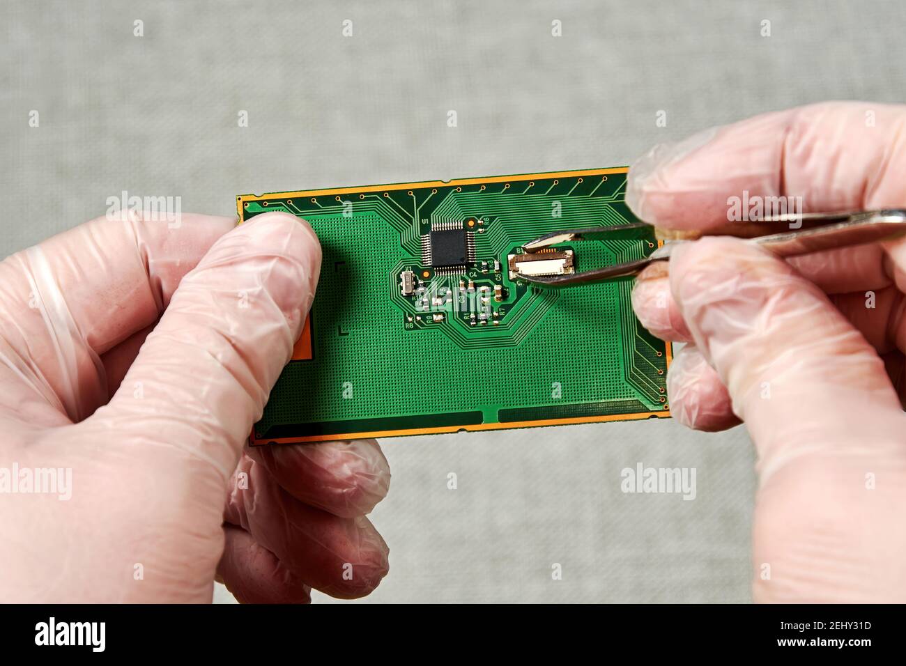 Un ingénieur équipé de pinces à épiler répare le circuit imprimé avec une petite puce. Concept des procédés de fabrication Banque D'Images
