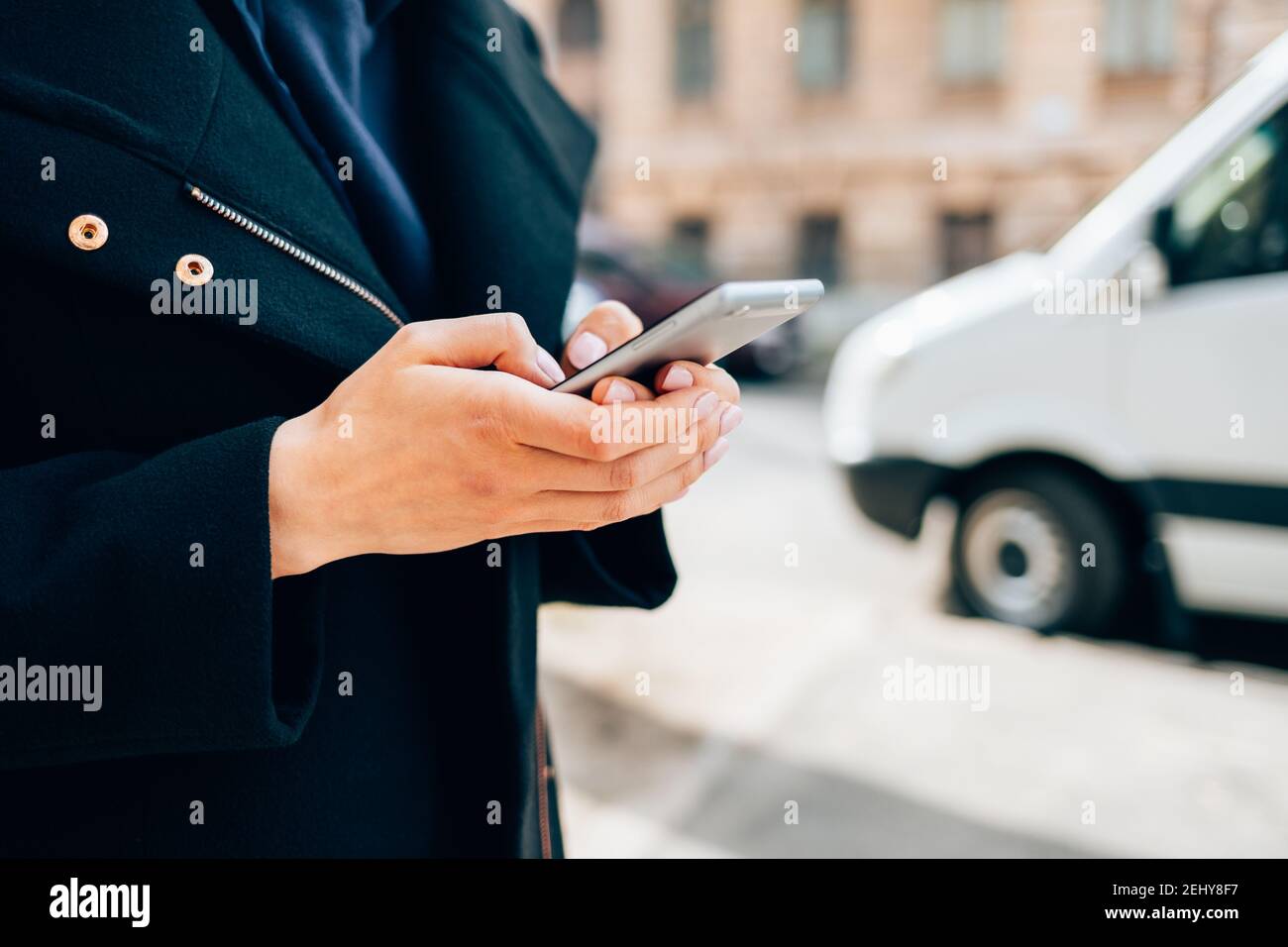 Une jeune femme en gros plan portant un manteau noir sur un téléphone portable Banque D'Images