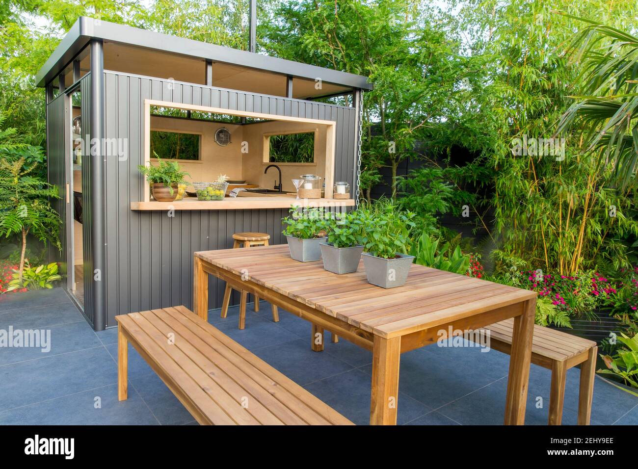 Jardin urbain extérieur espace de vie cuisine bar maison d'été sur le patio  pavé de pierre en graphite foncé, banc de jardin mobilier de table, menthe  en pots UK Photo Stock -
