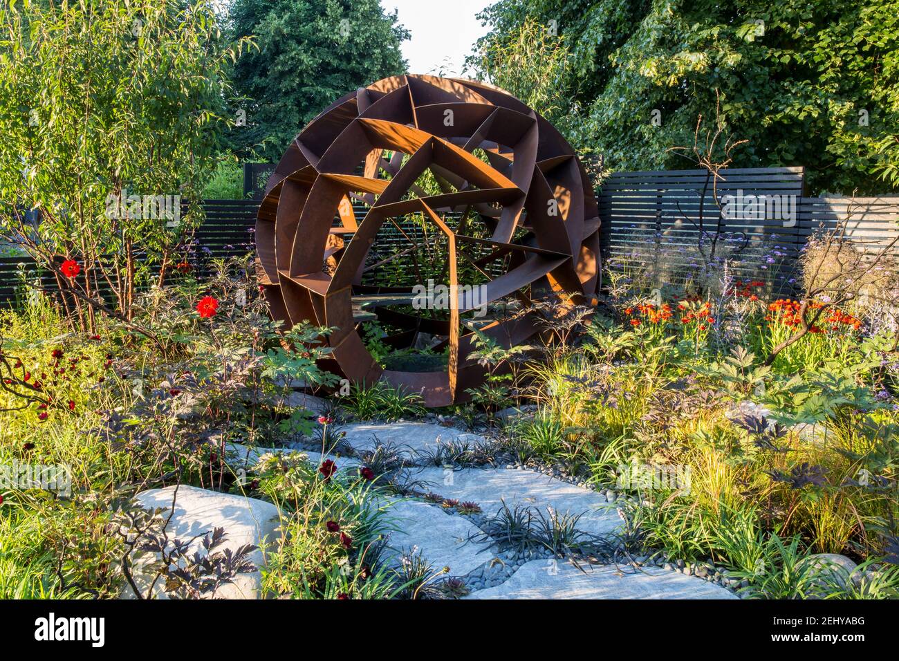 Jardin de gravier contemporain avec de grandes dalles de pavage en pierre calédonienne chemin structure en acier corten coin salon avec des parterres de fleurs d'été frontière Angleterre Royaume-Uni Banque D'Images