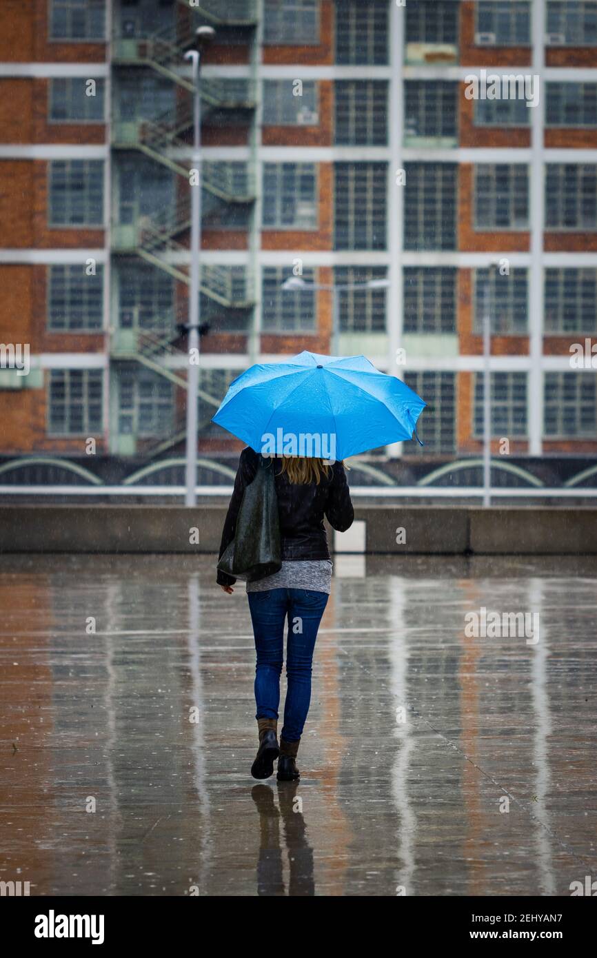 Femme avec parapluie marchant dans la ville sous la pluie. Femme tendance portant des vêtements décontractés de style urbain. La vie urbaine par mauvais temps Banque D'Images