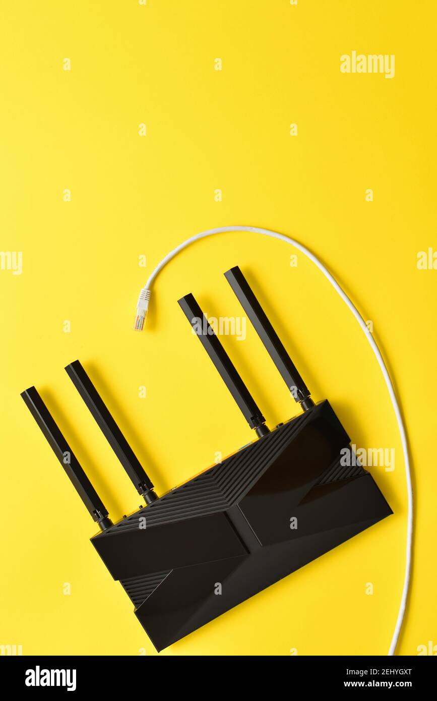 Routeur Wi-fi 6 noir moderne sur fond jaune avec câble ethernet Banque D'Images