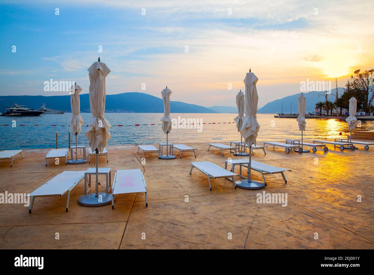 Terrasse au bord de la mer avec parasoles pliés au coucher du soleil, Tivat, Monténégro Banque D'Images