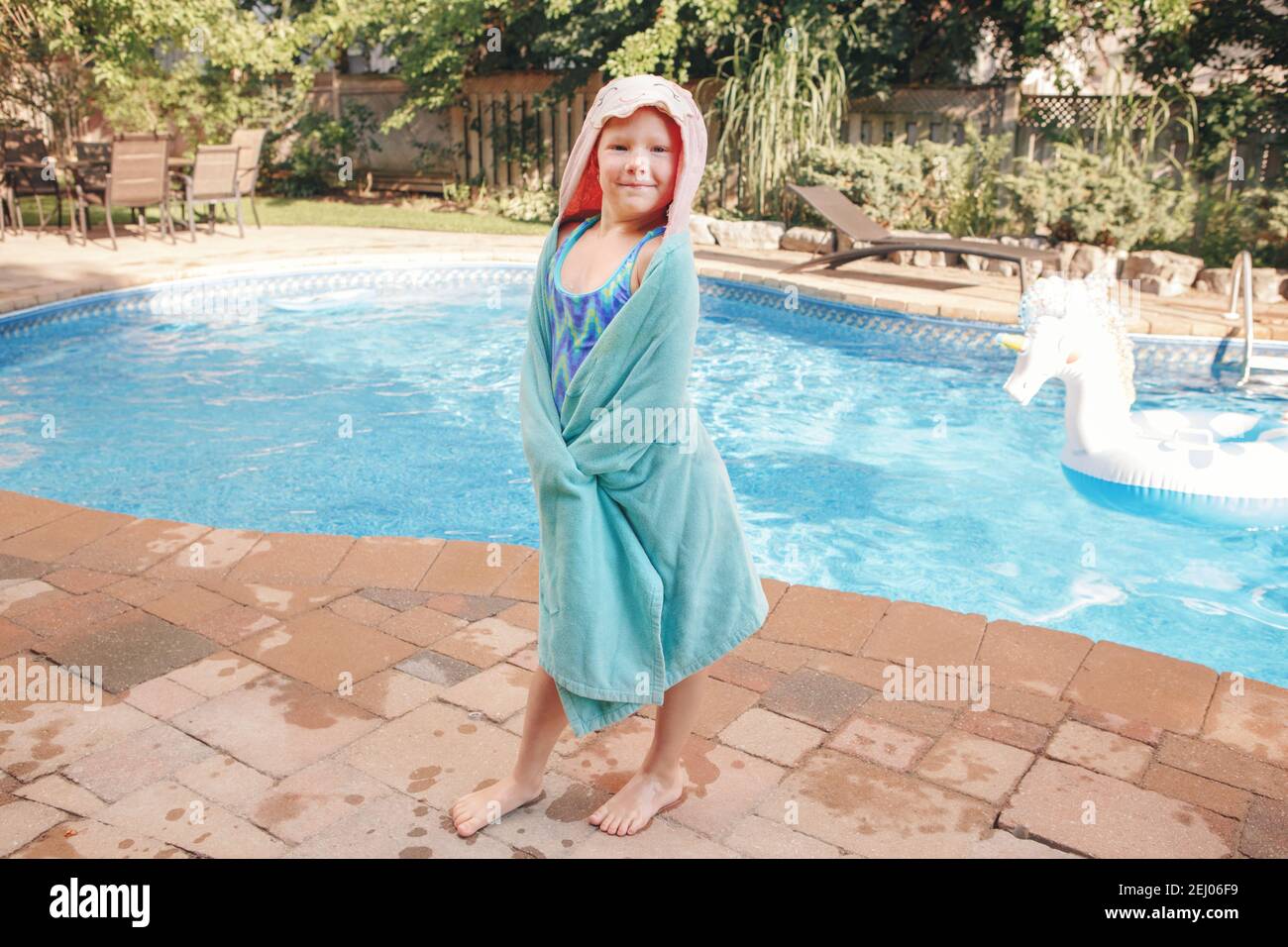 Jolie adorable fille avec des roussettes enveloppées dans une serviette de  plage au bord de la piscine. Sourire drôle enfant s'amuser dans la piscine.  Activités aquatiques extérieures en été Photo Stock -