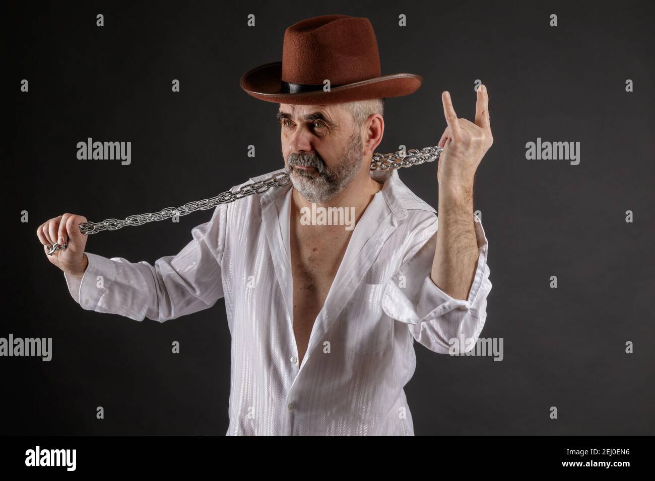 Un homme âgé à poil court barbu avec une chaîne métallique ses mains montrent une chèvre rockers Banque D'Images