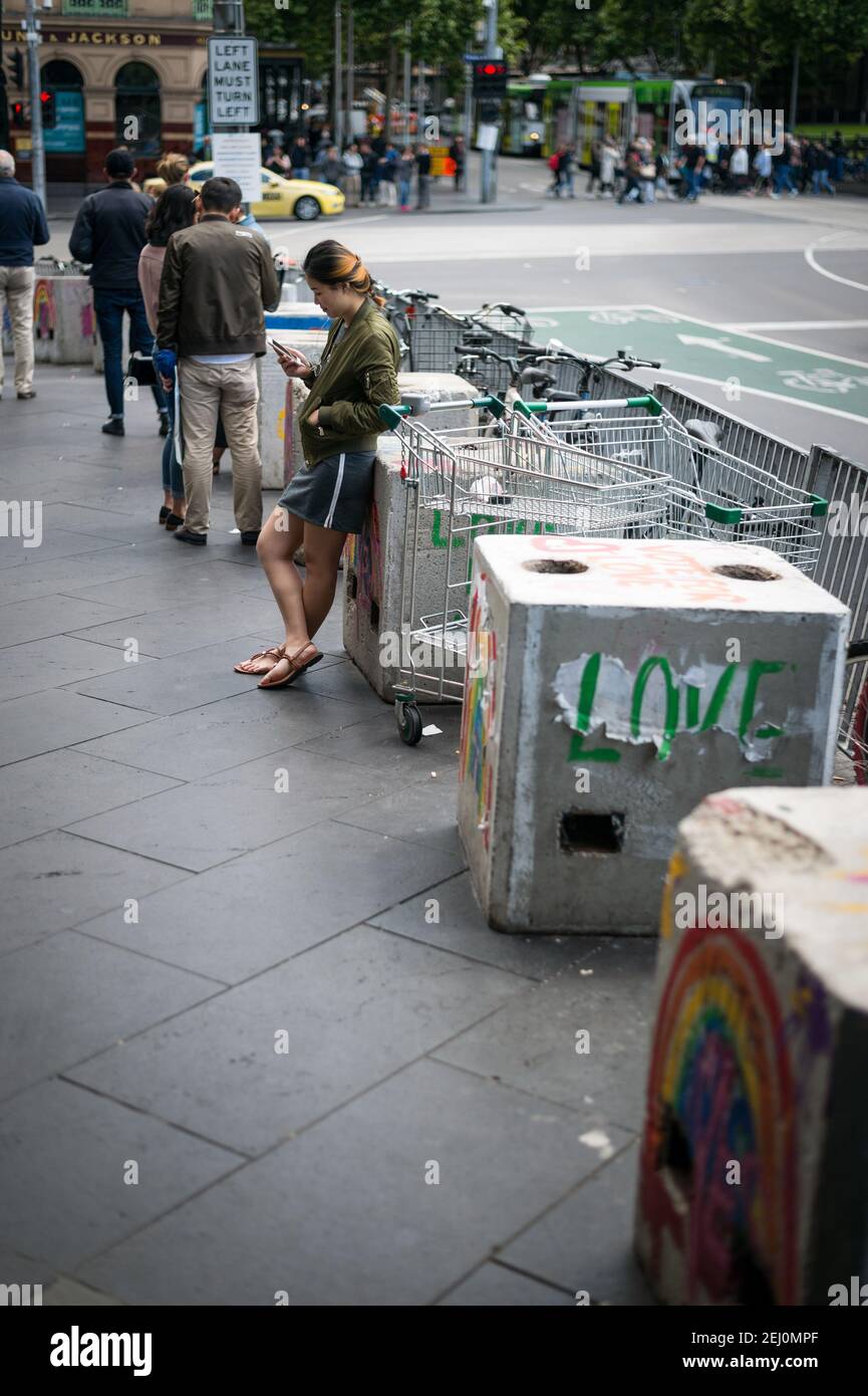 Une jeune femme vérifie son téléphone à l'extérieur de Flinders Street Station, Melbourne, Victoria, Australie. Banque D'Images