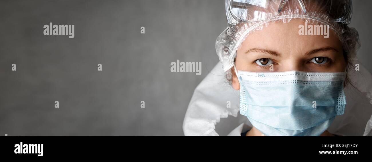 Bannière avec une femme médecin ou infirmière en costume d'EPI et espace de copie, femme portant des lunettes de protection et un masque médical pour le visage en raison de la pand du coronavirus COVID-19 Banque D'Images