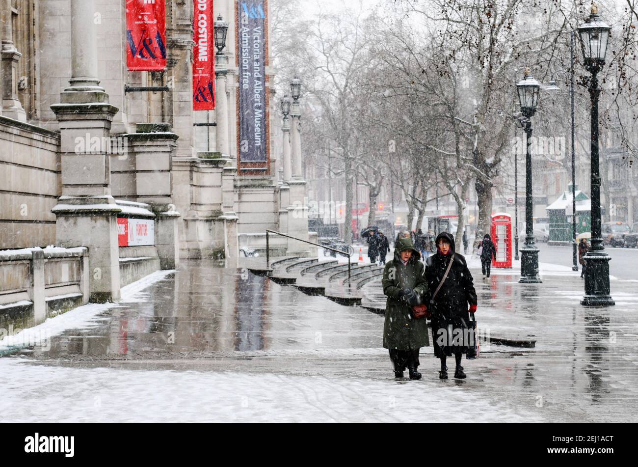 Les gens qui marchent dans les rues de Londres gelée tempête de neige neigeuse en hiver. Banque D'Images