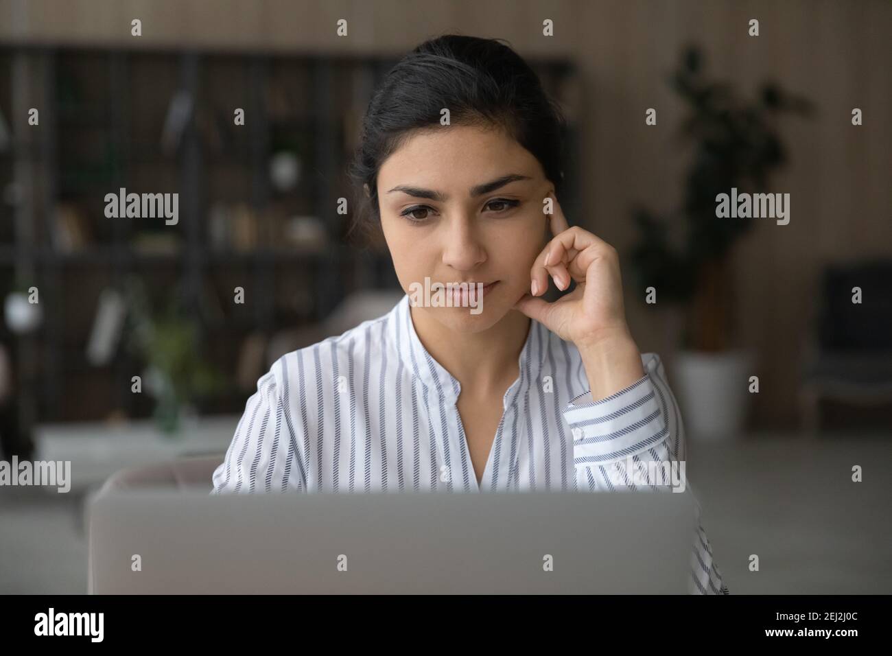 Une femme indienne pensive travaille sur un ordinateur portable Banque D'Images