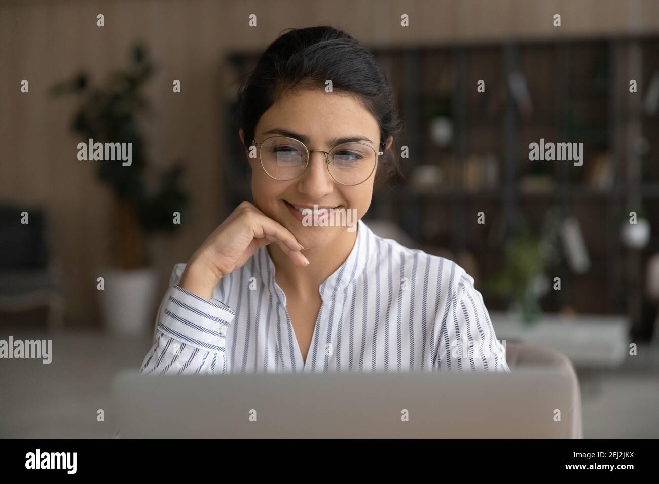 Femme indienne souriante travaille sur un ordinateur portable en ligne Banque D'Images