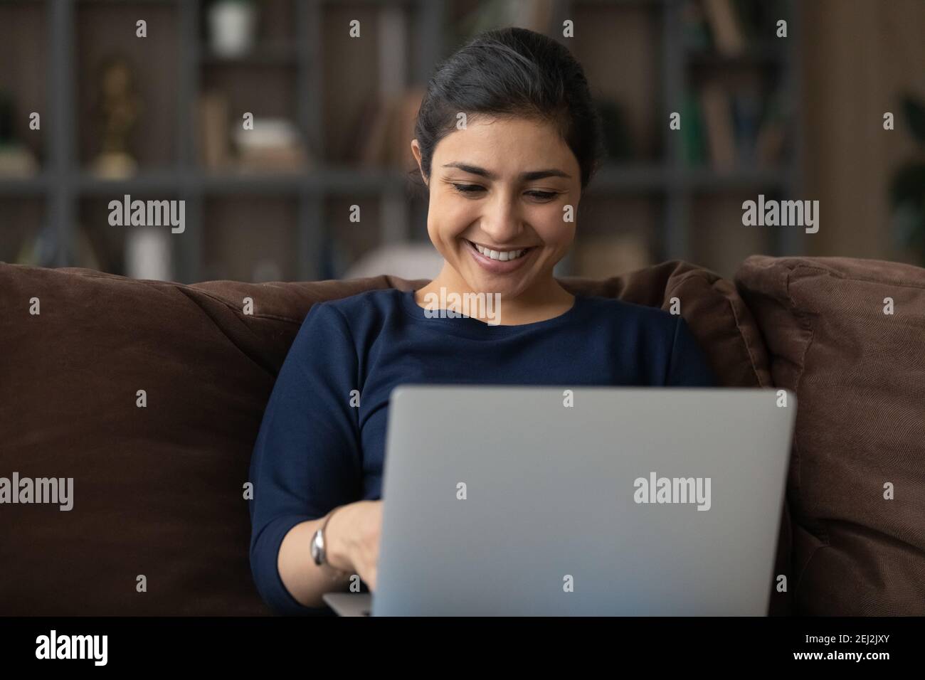 Femme indienne souriante travaillant sur un ordinateur portable à la maison Banque D'Images
