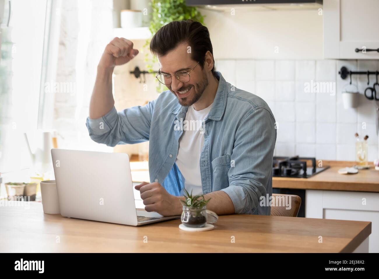 Un homme du millénaire excités célèbre son gain sur ordinateur portable Banque D'Images