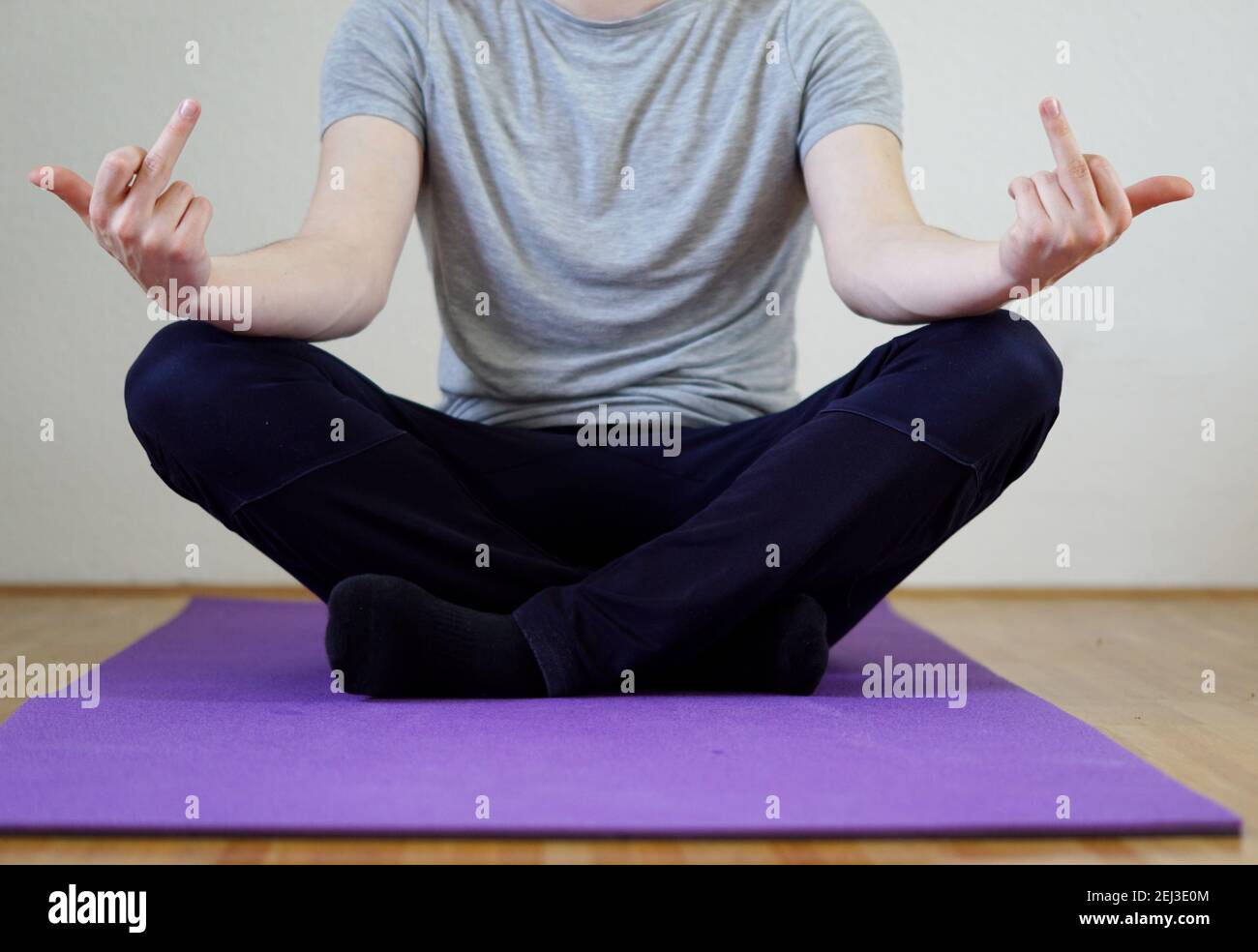 posture agressive passive - homme assis en position de yoga montrant doigt du milieu Banque D'Images