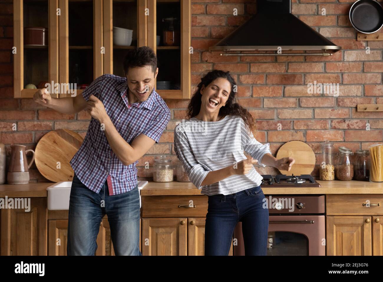 Un jeune couple joyeux dansant dans une cuisine moderne, s'amusant Banque D'Images