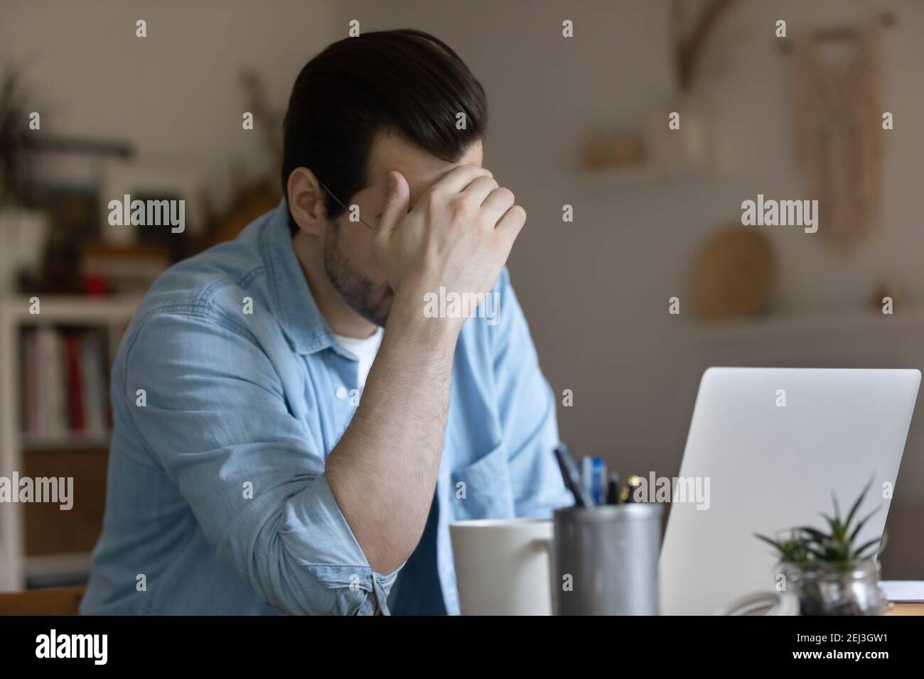 Un homme malheureux travaille sur un ordinateur portable qui a des problèmes Banque D'Images