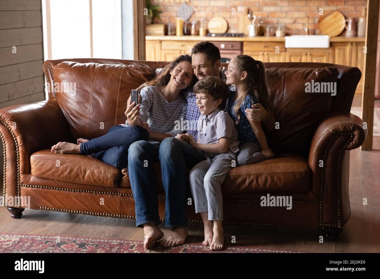 Une famille heureuse avec deux enfants qui font du selfie sur un smartphone Banque D'Images