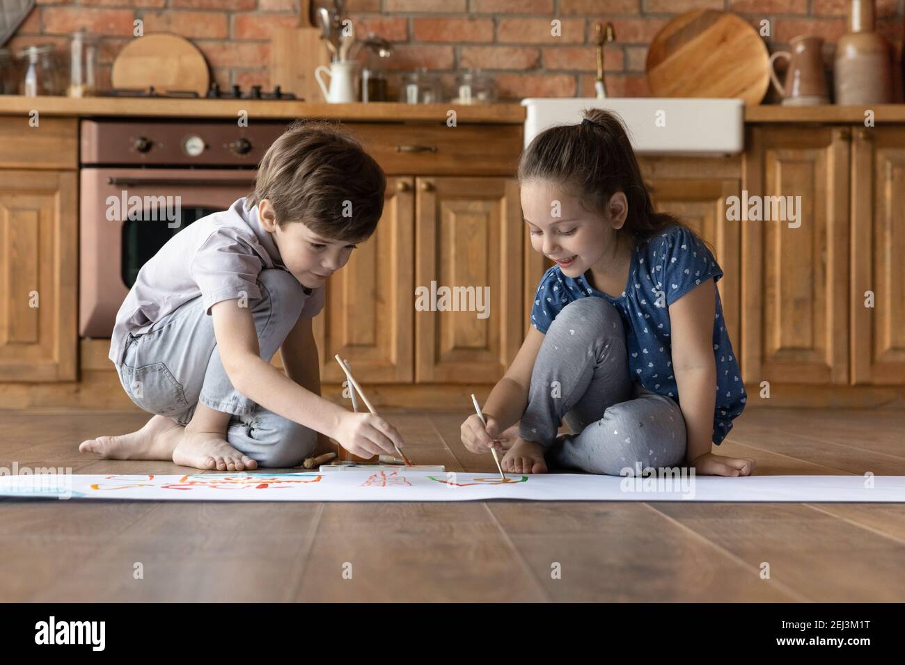 Deux petits enfants peignent de l'aquarelle colorée, assis sur le sol Banque D'Images