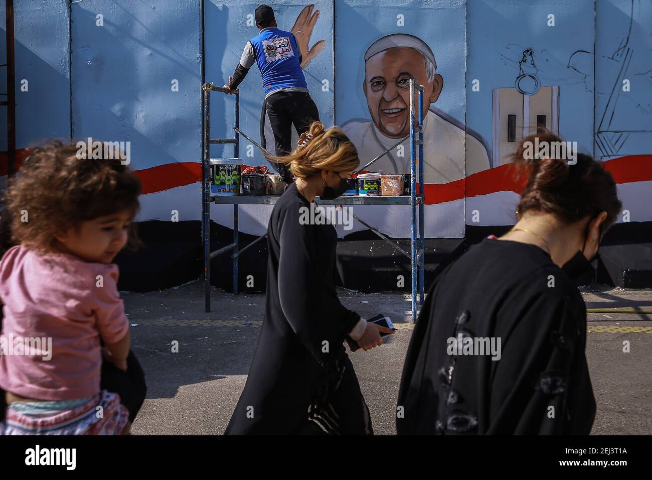 Bagdad, Irak. 21 février 2021. Amjad, un artiste iraquien de l'ONG 'Impressum of Hope', peint une fresque du Pape François sur le mur entourant l'Église catholique syriaque Sayidat al-Nejat (notre Dame de la livraison). Le pape François doit visiter l'église dans le cadre de son voyage en Irak du 05 au 08 mars 2021. Credit: Ameer Al Mohmedaw/dpa/Alamy Live News Banque D'Images